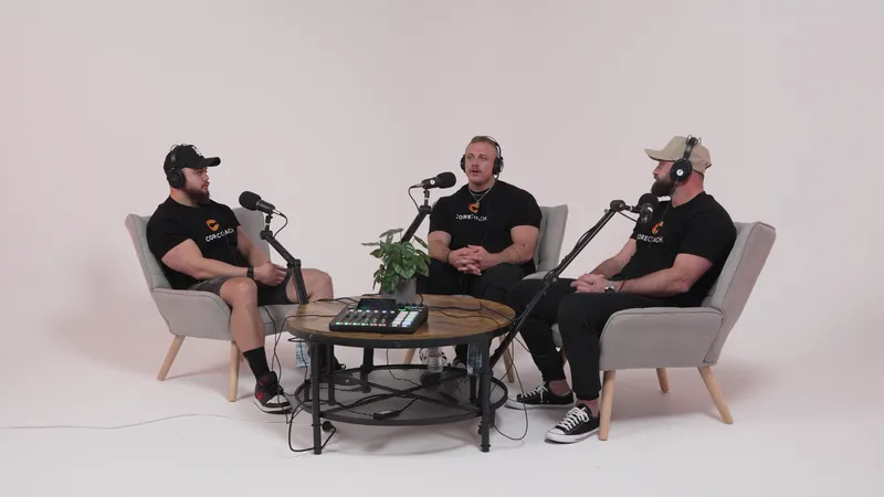 Three Core Coach hosts in armchairs round a timber table with a mixing desk, mics on arms, on the white Cyc