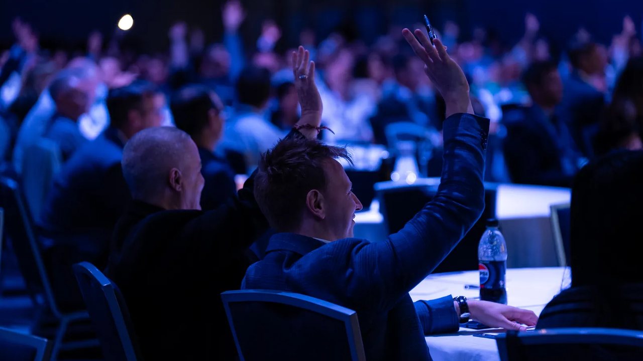 An audience member raising a hand during a session at an Australian Payments Network summit.