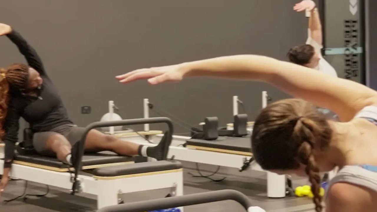 A Reformer Pilates class at World Gym, mid-stretch.