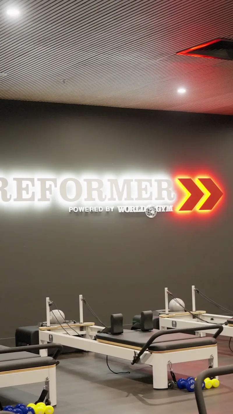 Reformer Pilates studio at a World Gym club with the neon sign lit
