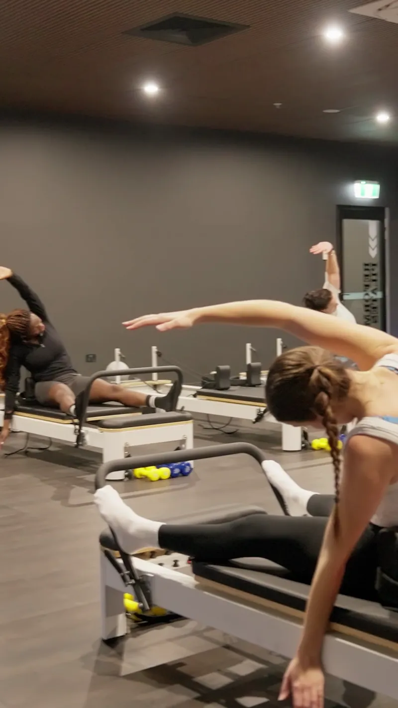 Member stretching on a reformer during a World Gym Pilates class